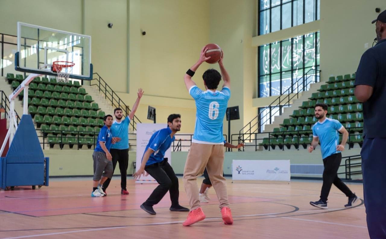 طالب يصوّب الكرة في مباراة كرة سلة داخل الصالة