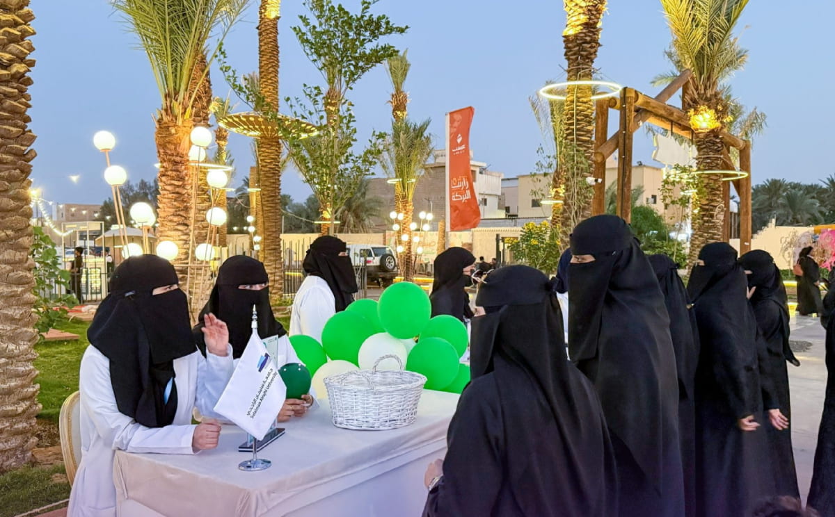 طالبات في معاطف بيضاء يستقبلن الزائرات عند ركن توعوي مسائي