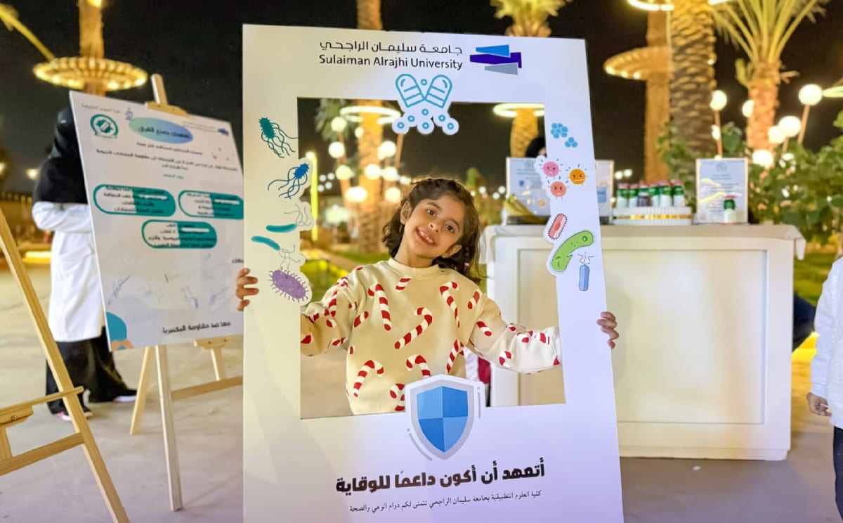 طفلة تحمل إطاراً تعريفياً في ركن التوعية بمقاومة المضادات الحيوية